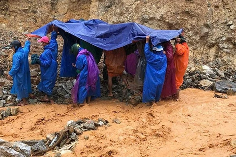 Lực lượng dân quân thường trực xã Trà Leng cùng người nhà dùng võng để khiêng bệnh nhân qua khu vực sạt lở.