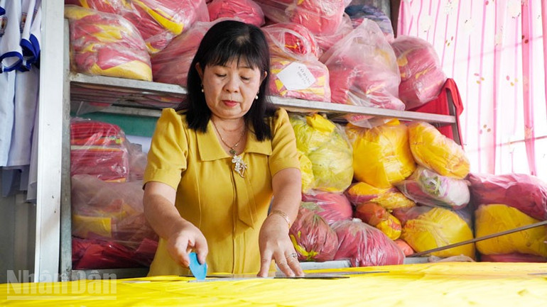 Bà Thu tỉ mỉ cắt hình ngôi sao vàng để may vào nền vải đỏ thành lá cờ Tổ quốc. ndo_bl_2.jpg