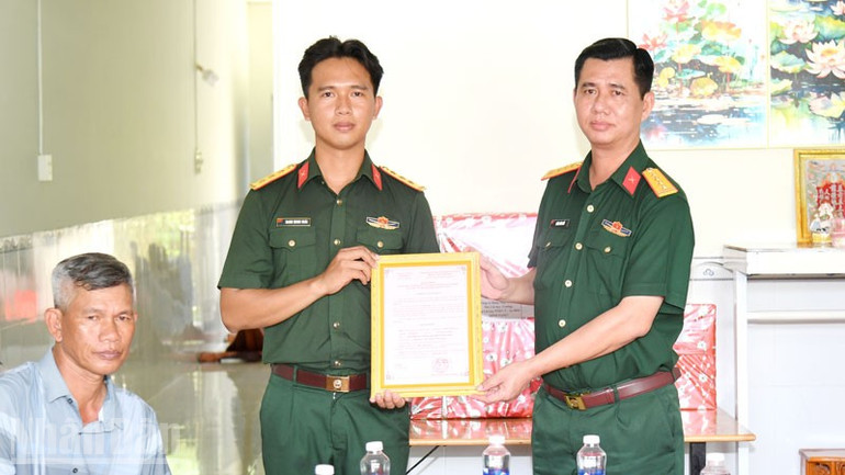 Đại tá Huỳnh Văn Khởi (bên phải), Chính ủy Bộ Chỉ huy Quân sự tỉnh An Giang trao quyết định bàn giao nhà đồng đội cho gia đình thượng úy Danh Minh Hoài. (Ảnh: PHƯƠNG VŨ) ndo_bl_2.jpg