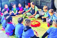 Học sinh đến trải nghiệm gói bánh tét mặt trăng ở làng Đại An Khê. (Ảnh: QUANG HUY)