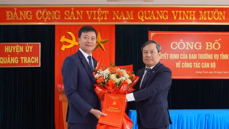 Bí thư Tỉnh ủy Quảng Bình Vũ Đại Thắng trao quyết định, tặng hoa chúc mừng Bí thư Huyện ủy Quảng Trạch Nguyễn Chí Thắng (bên trái).