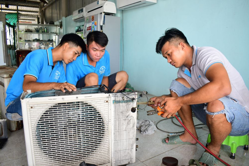 Sau khi học nghề điện lạnh, anh Trần Anh Vũ (bên trái) làm chủ kinh tế với thu nhập tăng cao.