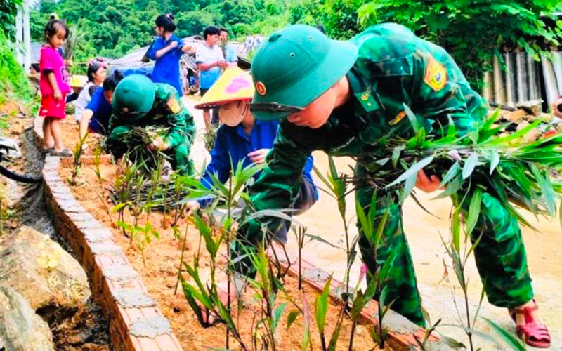Thanh niên cùng lực lượng vũ trang trồng hoa bên đường nội bản Con Dao, xã Quang Chiểu.