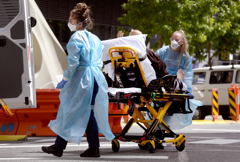 Nhân viên y tế chuyển bệnh nhân Covid-19 tới bệnh viện tại Melbourne, Australia. (Ảnh: AFP/TTXVN)