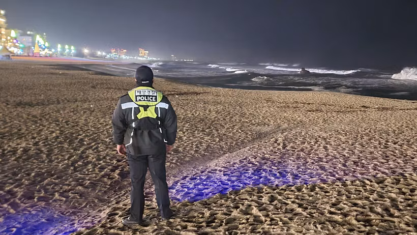 Một thành viên của lực lượng bảo vệ bờ biển Hàn Quốc theo dõi thay đổi của mực nước biển trên bãi biển ở Gangneung, Hàn Quốc, ngày 1/1/2024. (Ảnh: Yonhap/AP) 