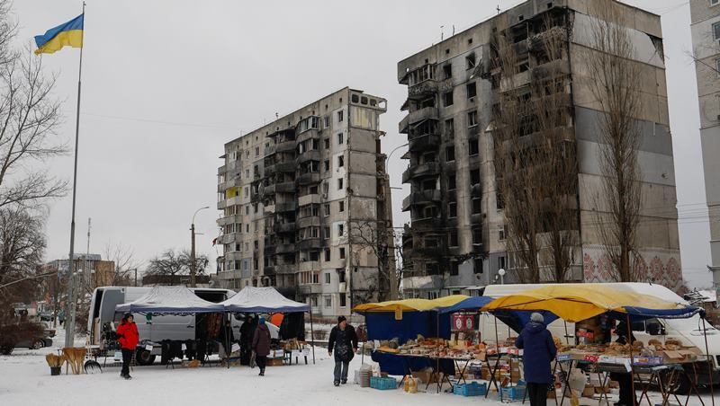 Người dân Ukraine mua thực phẩm tại một khu chợ đường phố phía trước tòa nhà chung cư bị hư hại tại thị trấn Borodianka, tỉnh Kiev, Ukraine, ngày 15/12/2022. (Ảnh: Reuters)