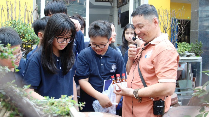 Anh Bùi Thanh Phú (ngoài cùng bên phải) giới thiệu với học sinh về nghề làm nước mắm.