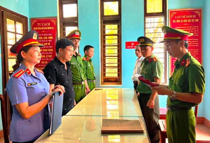 Nguyễn Quốc Trung, Giám đốc Công ty TNHH Thạch Phú Hưng (áo đen, thứ 2 từ trái sang) nghe đọc lệnh khởi tố. (Ảnh: Công an cung cấp)