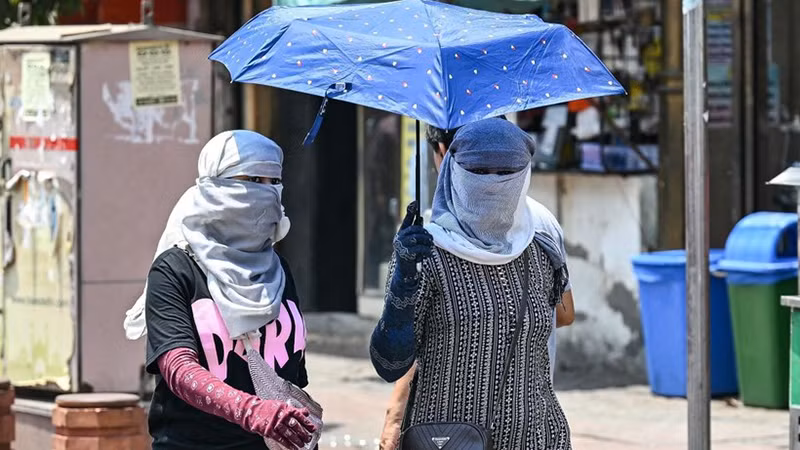 Người dân di chuyển dưới trời nắng nóng tại New Delhi, Ấn Độ. (Ảnh: AFP/TTXVN)
