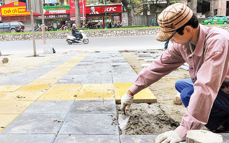 Công nhân lát đá vỉa hè trên tuyến phố Giảng Võ, quận Ba Đình. (Ảnh DOÃN THÀNH)