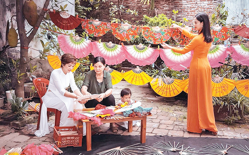 Nghệ nhân Nguyễn Thị Tuấn (áo sẫm) giới thiệu về nét đẹp quạt Chàng Sơn đến khách du lịch.