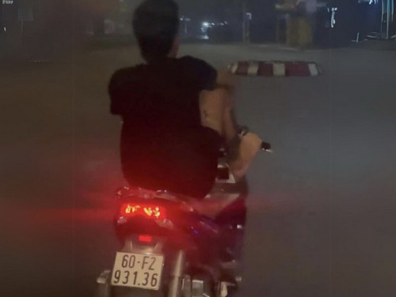 Võ Văn Tâm dùng chân điều khiển xe máy trên đường Hà Huy Giáp.