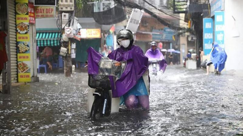 Người dân phải dắt bộ xe máy vì không thể di chuyển trong tình trạng ngập úng nặng. (Ảnh: PV/Vietnam+)