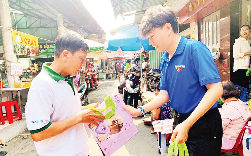 Tình nguyện viên nhóm Go Volunteer phát bao bì thân thiện với môi trường cho người dân tại xã Tân Thông Hội, huyện Củ Chi. 