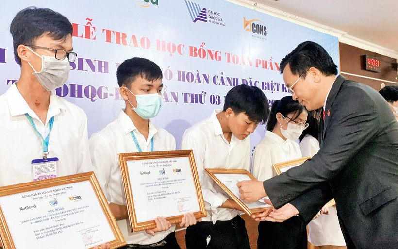 PGS, TS Nguyễn Ðình Tứ, Giám đốc Quỹ Phát triển Ðại học Quốc gia Thành phố Hồ Chí Minh trao học bổng tặng sinh viên mồ côi, khó khăn. (Ảnh: Ðại học Quốc gia Thành phố Hồ Chí Minh). 