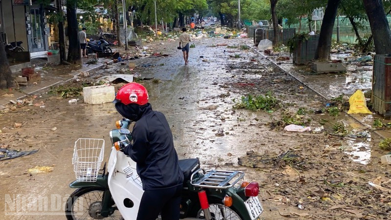 Người dân quay đầu xe trước con đường ngập rác thải sau lụt.