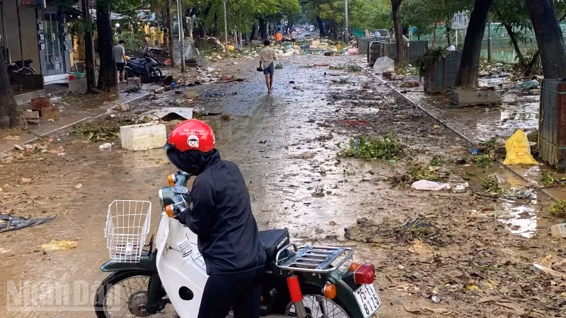 Người dân quay đầu xe trước con đường ngập rác thải sau lụt.