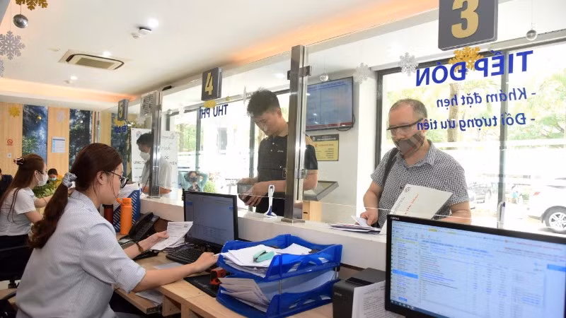 Nhân viên Bệnh viện Ung bướu Hà Nội hướng dẫn bệnh nhân làm các thủ tục khám, chữa bệnh bảo hiểm y tế. (Ảnh: KHÁNH AN)