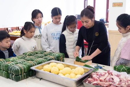 Các cháu thanh thiếu niên, nhi đồng chăm chú theo dõi các khâu gói bánh chưng.