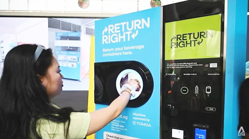 Một người tiêu dùng đặt chai nhựa rỗng vào máy thu gom. Ảnh: CNA