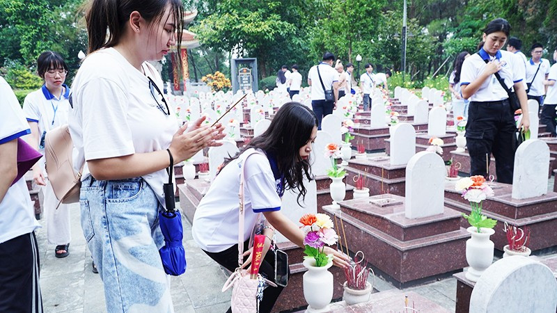 Thanh niên kiều bào thắp hương tưởng nhớ các anh hùng liệt sĩ tại Nghĩa trang Trường Sơn. Ảnh: NVNONN