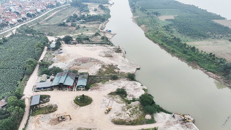Cụm bến bãi tập kết cát nằm sâu trong một nhánh sông Hồng thuộc Công ty Cổ phần Thương binh Thành Luân, tách biệt khu dân cư, các mố cầu cảng được đắp dựng vươn ra sông để phục vụ việc vận chuyển cát từ dưới sông lên bãi. Ảnh chụp ngày 28/12/2025.