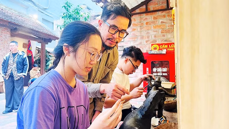 Họa sĩ Nguyễn Tấn Phát hướng dẫn các bạn trẻ thực hành với sơn mài tại đình Hà Vĩ.