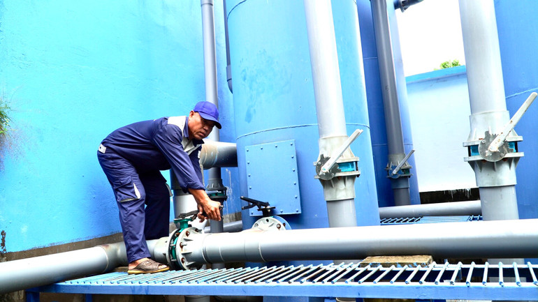 Nhân viên Công ty TNHH Cấp thoát nước Ngọc Lợi, xã An Phong, huyện Thanh Bình (Đồng Tháp) vận hành cụm lọc nước trọng lực. (Ảnh: Hữu Nghĩa)
