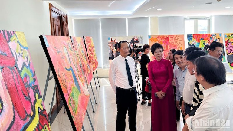 Các đại biểu và khán giả chiêm ngưỡng bộ tranh của hoạ sĩ Phạm Hải Nguyên được trưng bày.