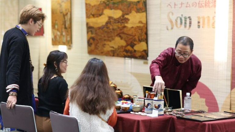 Họa sĩ Lương Minh Hòa hướng dẫn khách khắc, thếp bạc, mài để tạo nên một bức sơn mài khắc làm kỷ niệm. (Ảnh: Bộ Ngoại giao Việt Nam)