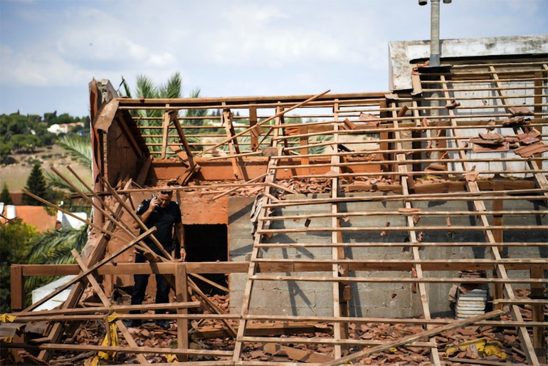 Một cảnh sát Israel đi giữa đống đổ nát của một ngôi nhà bị trúng rocket được phóng từ Lebanon.