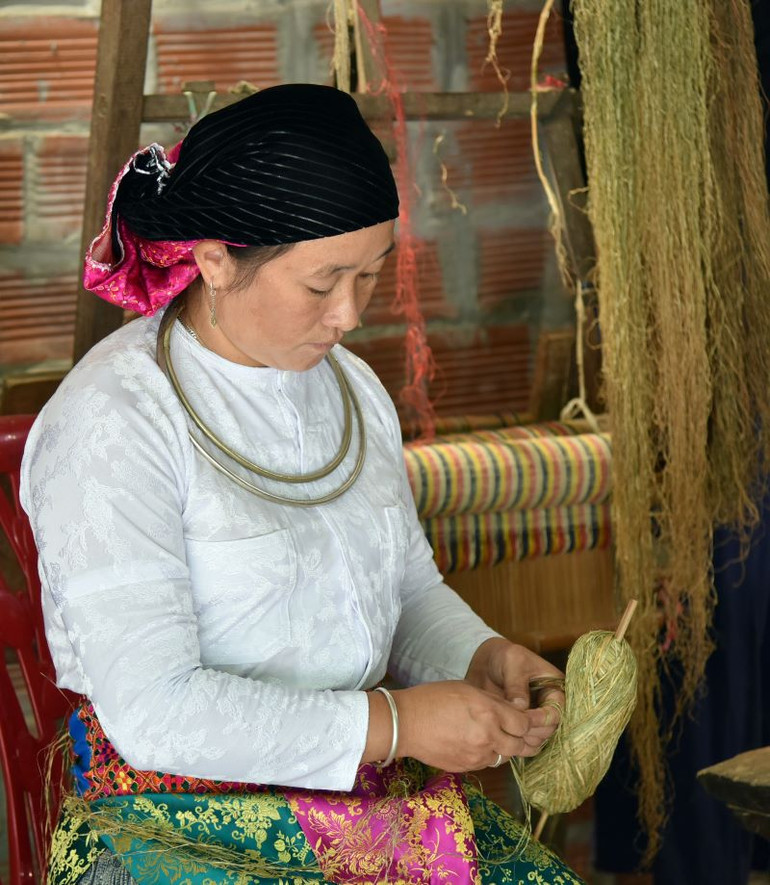 Phụ nữ H’Mông tranh thủ cuốn sợi lanh những lúc nhàn rỗi.