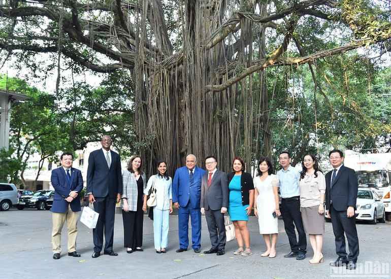 Tổng Biên tập Báo Nhân Dân Lê Quốc Minh và Phó Tổng Biên tập Báo Granma Arlin Alberty Loforte cùng cán bộ của hai cơ quan báo chí chụp ảnh lưu niệm bên gốc cây đa trong khuôn viên Báo Nhân Dân. (Ảnh: THỦY NGUYÊN)