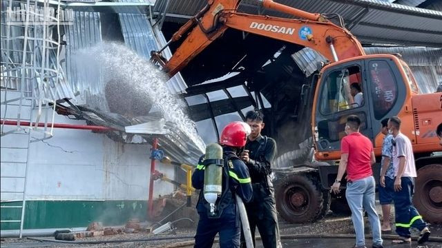 Các lực lượng chức năng phá hàng rào tôn để dập lửa.