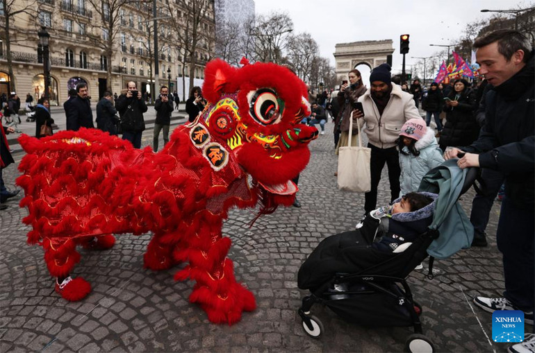 Người dân hào hứng theo dõi tiết mục múa sư tử trên Đại lộ Champs Elysee, Paris, Pháp. Ảnh: TÂN HOA XÃ