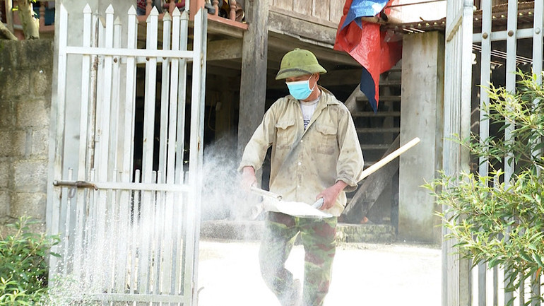 Người dân tiến hành rắc vôi khử trùng khu vực xung quanh nhà ở theo hướng dẫn.