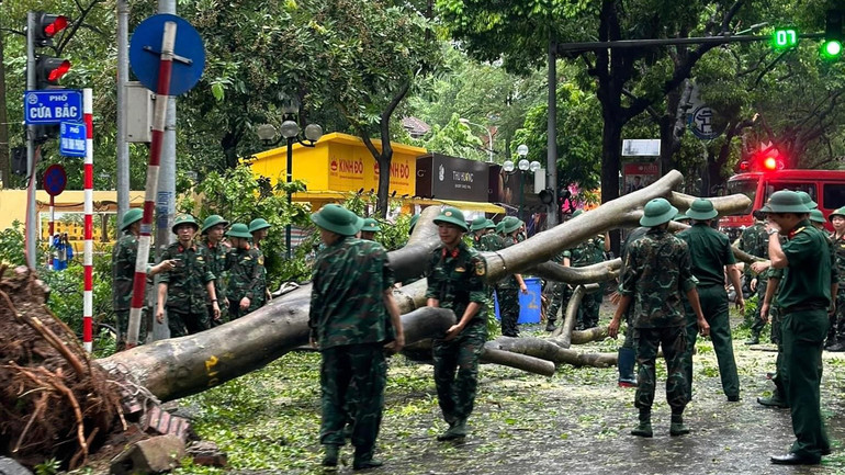 Lực lượng chức năng xử lý cây đổ trên đường Lý Thường Kiệt và ngã tư Phan Đình Phùng giao Cửa Bắc. (Ảnh: PHÙNG TRANG)