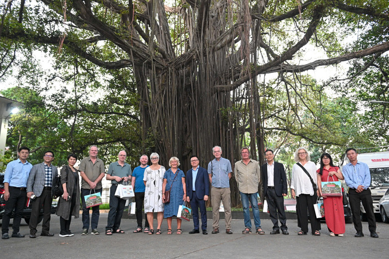 Lãnh đạo Báo Nhân Dân và Đoàn đại biểu FOJO chụp ảnh lưu niệm bên Cây đa 71 Hàng Trống. (Ảnh: THẾ ĐẠI)