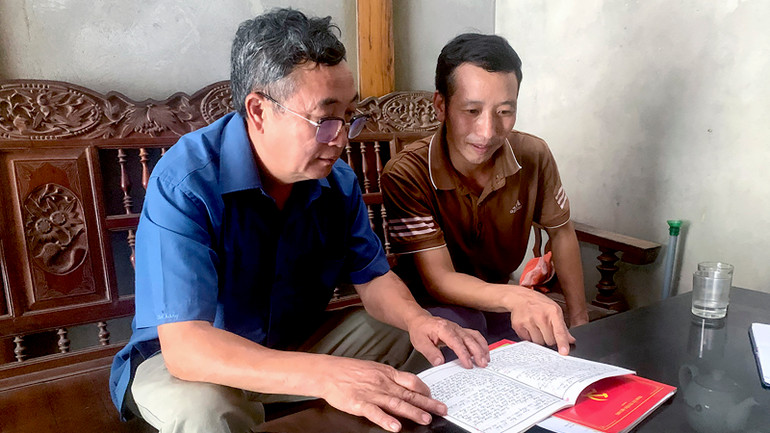 Bí thư Chi bộ thôn Nà Tang, xã Hùng Lợi, huyện Yên Sơn Lầu Văn Thào (bên trái) trao đổi, hướng dẫn đảng viên trẻ trong chi bộ.