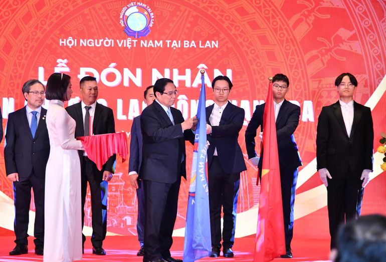 Thủ tướng Phạm Minh Chính gắn Huân chương Lao động hạng Ba lên cờ truyền thống của Hội Người Việt Nam tại Ba Lan (Ảnh: THANH GIANG).