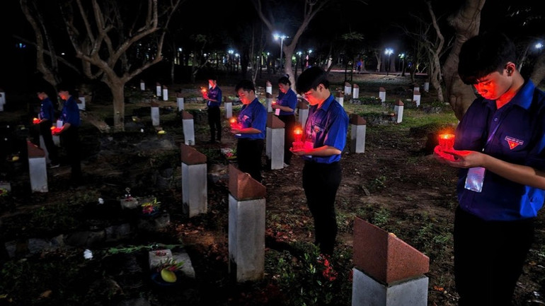 Các đoàn viên thanh niên thắp nến tri ân tại phần mộ các anh hùng liệt sĩ. (Ảnh: VŨ TÂN)
