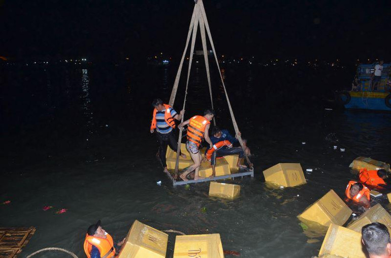 Lực lượng bốc xếp cùng với nhân viên trên tàu vớt hàng hóa bị rơi xuống nước đưa lên bờ.