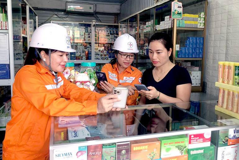 Cán bộ công ty Điện lực Tuyên Quang hướng dẫn người dân thanh toán tiền điện không dùng tiền mặt qua các ứng dụng.