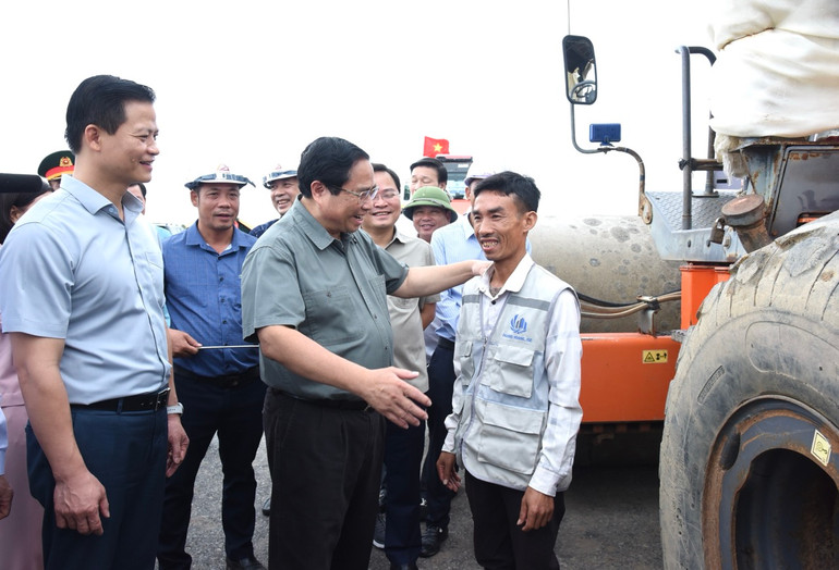 Thủ tướng Phạm Minh Chính hỏi thăm, động viên một công nhân lái xe lu đang thi công tại Dự án đường Vành đai 4 - Vùng Thủ đô Hà Nội đoạn qua huyện Thuận Thành, tỉnh Bắc Ninh.