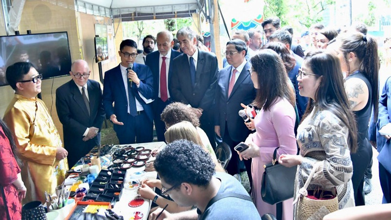 Thủ tướng Phạm Minh Chính và các đại biểu nghe giới thiệu về cách làm tranh sơn mài. (Ảnh: Thanh Giang)