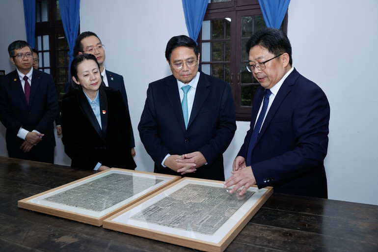 Lãnh đạo Khu Di tích lịch sử Hồng Nham giới thiệu với Thủ tướng Phạm Minh Chính về 2 tờ Tân hoa báo có bài viết của Chủ tịch Hồ Chí Minh khi hoạt động cách mạng tại đây. (Ảnh: VGP/Nhật Bắc)