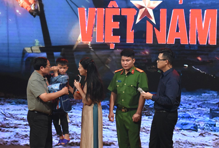 Thủ tướng Phạm Minh Chính lên sân khấu động viên cháu Nguyễn Quốc Bảo. (Ảnh: TRẦN HẢI)