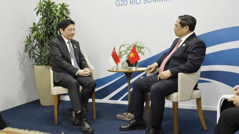 Thủ tướng Phạm Minh Chính trao đổi với Thủ tướng Singapore Laurence Wong. (Ảnh: Dương Giang/TTXVN)