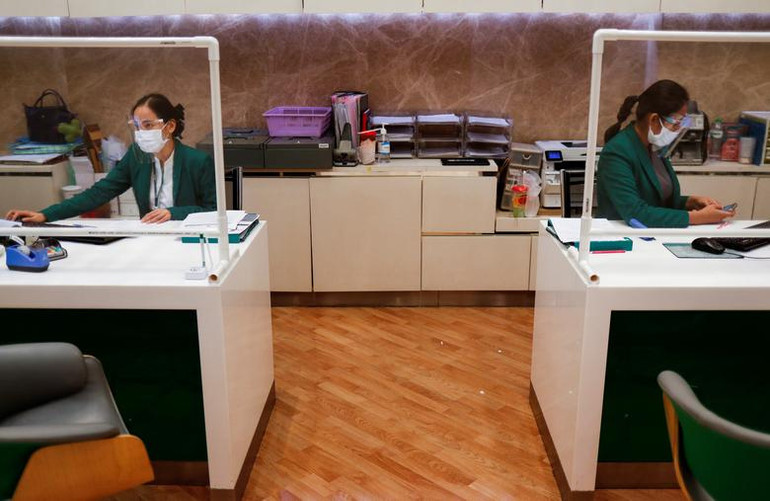 Nhân viên đeo tấm chắn và khẩu trang khi ngân hàng tại Bangkok (Thái Lan) chuẩn bị mở cửa trở lại vào ngày 14/5/2020. (Ảnh: Reuters)