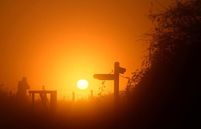 Khách tham quan chụp lại cảnh hoàng hôn trong màn sương mù tại công viên quốc gia South Downs, gần Petersfield, Anh, ngày 1/12. (Ảnh: Reuters)